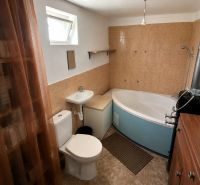 A bathroom in a cabin with a bathtub, sink, toilet, and a window for natural light.
