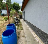 A cottage in Skalica with a side area and blue barrels by the fence.