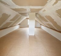 Attic space in a cottage with a wooden decor floor and slanted walls.