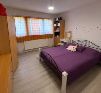 A bedroom in a family house with a bed, wardrobes, and a floor with a wooden decor.