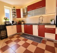 A kitchen in a family house with red and white cabinets, and a wooden decor floor.
