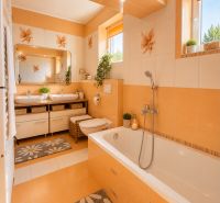 A bathroom with orange and white tiles, a double sink, and a bathtub in a family house.