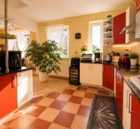 A bright kitchen in a family house with red cabinets and a wood-patterned floor.