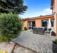 The garden of a family house in Bernolákovo with a stone terrace and outdoor seating.