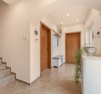 A hallway with tiles and a staircase, entrance to rooms in a family house.