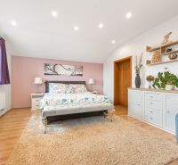 Bright bedroom in a family house with colorful decorative elements and a wooden-patterned floor.
