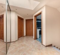 A hallway of a family house with tiles, a mirror, and four doors.