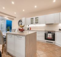 A kitchen in a family house with an island, white cabinets, and dining area.