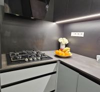 A kitchen in a 2-room apartment with a dark kitchen unit and a gas stove.