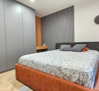 Bedroom with a bed, nightstand, and wardrobe in a 2-room apartment; floor with a wooden decor.