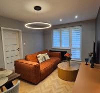 2-room apartment with an orange sofa and a round table, floor with wooden decor.