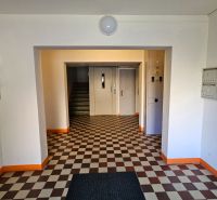 The entrance hall of an apartment building with numerous mailboxes and a checkered floor.