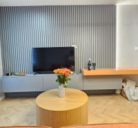 Living room in a 2-room apartment with a television, wooden floor decor, floral decoration.