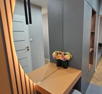 Entrance hallway in a 2-room apartment with a decorative mirror, flowers, and lighting.