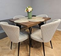 Dining table with four chairs and a wooden-patterned floor in a two-room apartment.