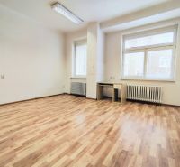 Bright office with wood-patterned flooring, a desk, and white walls.