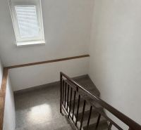 A staircase in a family house with a small window and neutral decor.