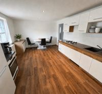 A kitchen in a family house with a wooden decor floor and a dining area.