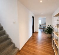 A hallway in a family house with a carpeted staircase and a wooden decor floor.