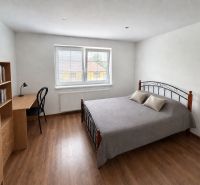 Bedroom in a family house with a metal bed, a desk, and a floor with a wooden decor.