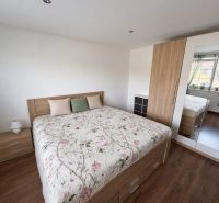 Bright bedroom in a family house with a bed, cabinets, and wooden decor flooring.