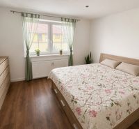 A bedroom with a bed, wardrobe, and wooden decor flooring in a family house.