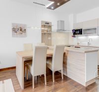 A kitchen in a 2-room apartment with a dining table and a wooden-patterned floor.