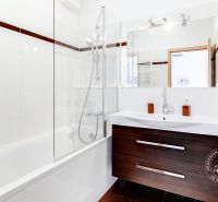 Bathroom in a 2-room apartment with a bathtub, glass screen, and sink.