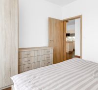 Bedroom in a 2-room apartment with white walls, a wardrobe, and a door to the kitchen.