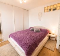 A bedroom in a 3-room apartment with a wooden decor floor and a purple blanket.
