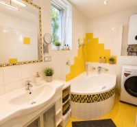 A bathroom in a 3-room apartment with a corner bathtub, washing machine, and cheerful yellow tiles.