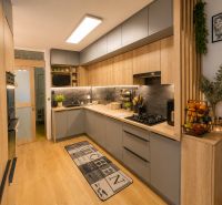 A kitchen in a 3-room apartment with a wooden decor floor and modern furnishings.