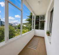 A glazed balcony in a 3-room apartment with a view of gardens and an industrial zone.