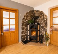 A wood-burning stove in a 3-room apartment with a stone wall and a floor with a wooden decor.