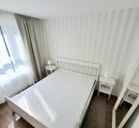 A bright bedroom with a white bed and a wooden decor floor in a 2-room apartment.