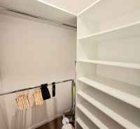A wardrobe with a shelving system and a hanger holder in a 2-room apartment with a wooden decor floor.