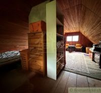 Attic room with wooden paneling, a wardrobe, and a floor with a wooden decor in a family house.