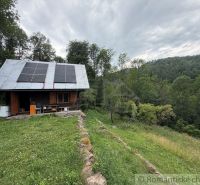 A family house in Kokava nad Rimavicou, with a lawn, solar panels, and surrounded by forest.