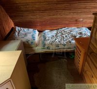 A bedroom in a family house with wooden walls, a bed, and a wardrobe.