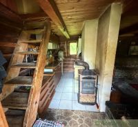 Interior of a family house with wooden stairs, a kitchen unit, and a tiled stove.