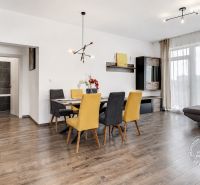 Dining area with yellow and gray chairs on a wooden decor floor in a 3-room apartment.