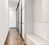 A hallway with mirrored wardrobes, white walls, and a wooden decor floor in a 3-room apartment.