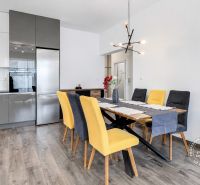 A kitchen with a wooden decor floor and colorful chairs in a 3-room apartment.