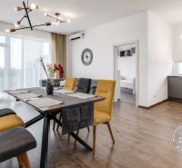 Dining table with colorful chairs and a wooden-patterned floor in a 3-room apartment.