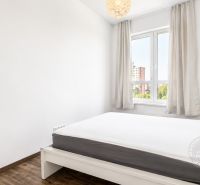 Bedroom with a bed, wooden decor flooring, and a window in a three-room apartment.