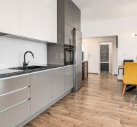 A kitchen with a dining area, wooden decor flooring in a 3-room apartment.
