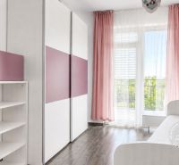 A children's room with pink curtains and a wooden decor floor in a 3-room apartment.