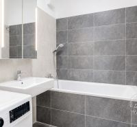 Bathroom in a 3-room apartment with a bathtub, sink, washing machine, and mirror.