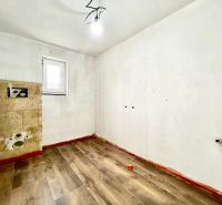 An empty room in a family house with a wooden decor floor and white walls.