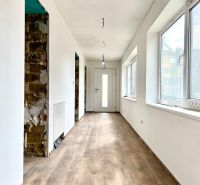 A hallway in a family house with a wooden decor floor and white walls.